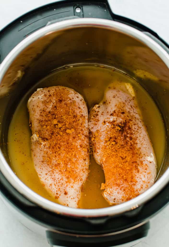 Chicken breasts with seasoning and broth in an Instant Pot