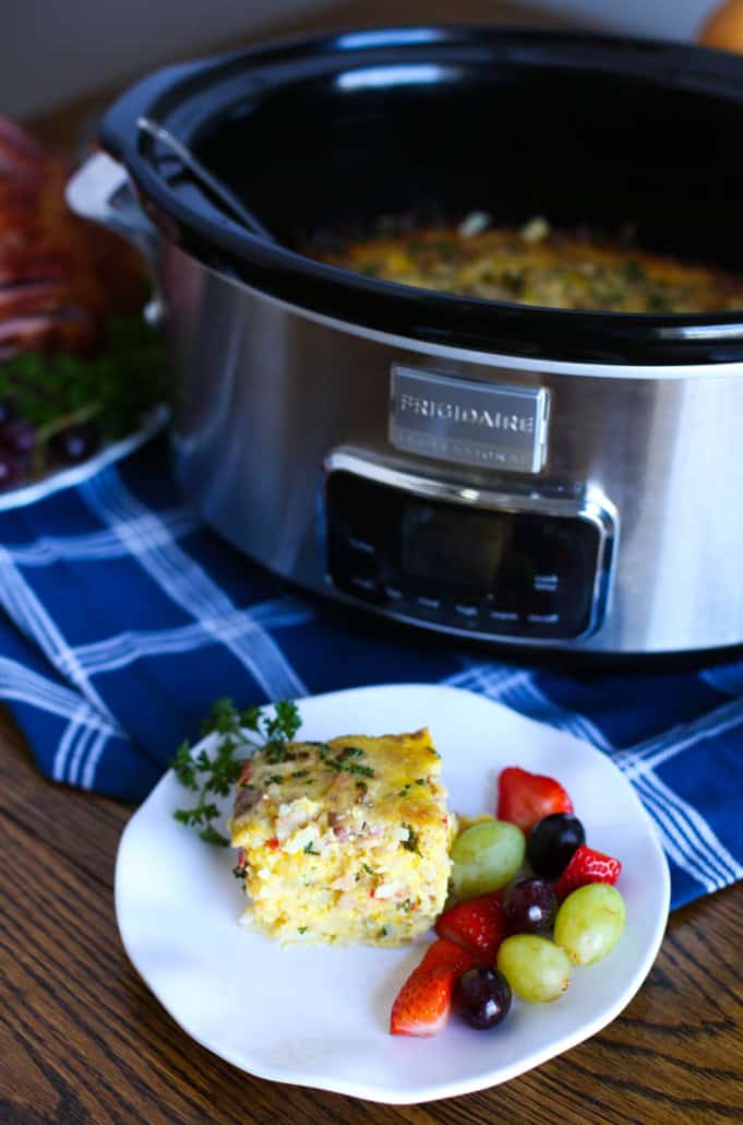 Breakfast Casserole slice on a plate with fruit and a slow cooker in the background