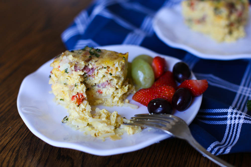 Breakfast Casserole slice on a plate with fruit and a fork