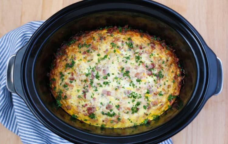 Breakfast Casserole in a Crockpot on a wooden cutting board.