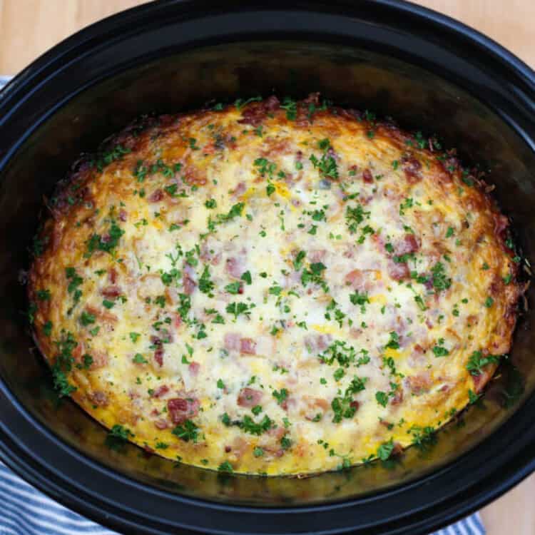 Breakfast Casserole in a Crockpot on a wooden cutting board.