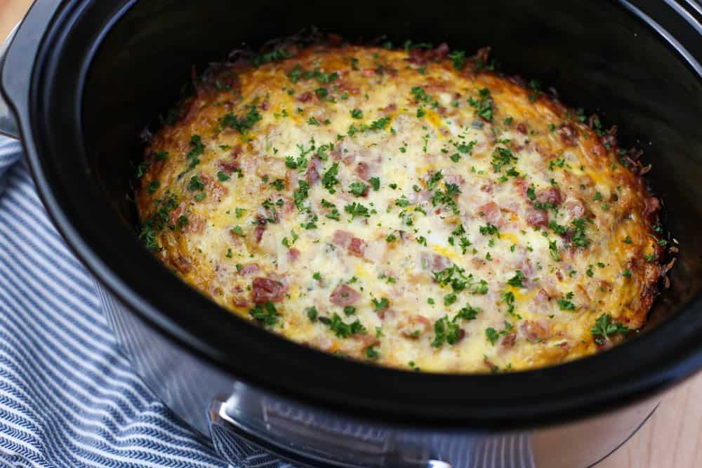 Breakfast Casserole in a slow cooker on a wooden cutting board