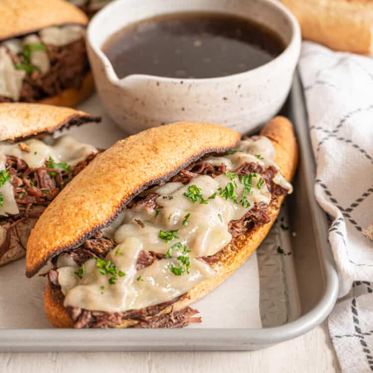 French dip sandwiches on a tray with a bowl of au jus.