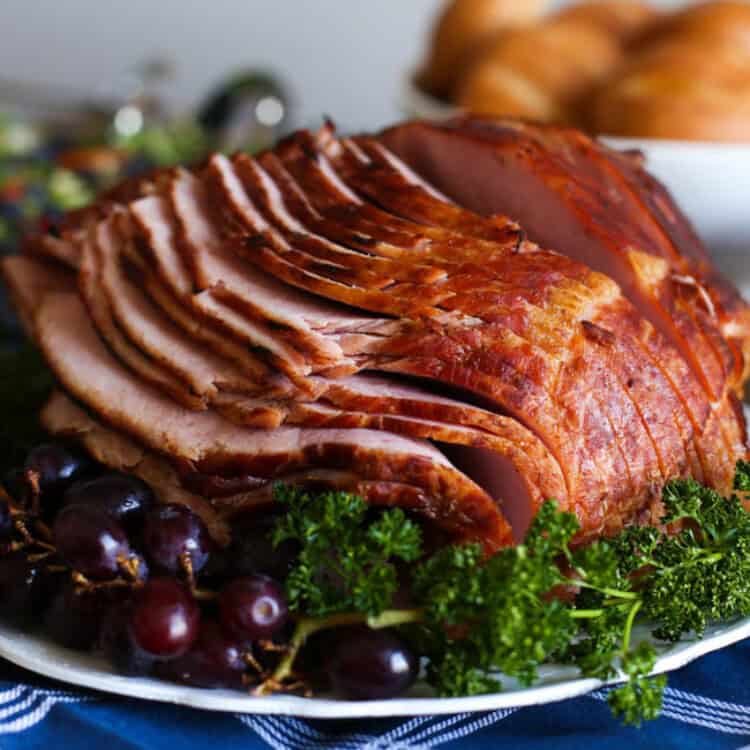 Spiral sliced ham on a serving dish with parsley and grapes.