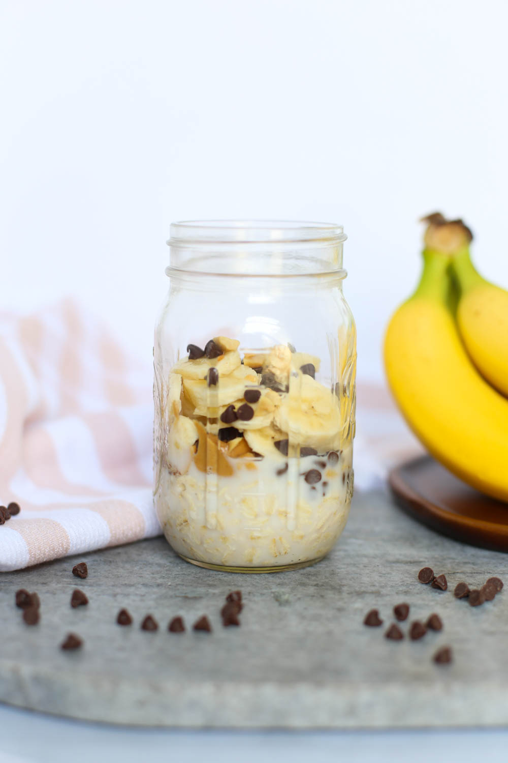 Overnight oats with peanut butter, mini chocolate chips, and sliced bananas in a mason jar.