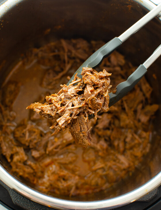 BBQ shredded beef in an Instant Pot with BBQ sauce.