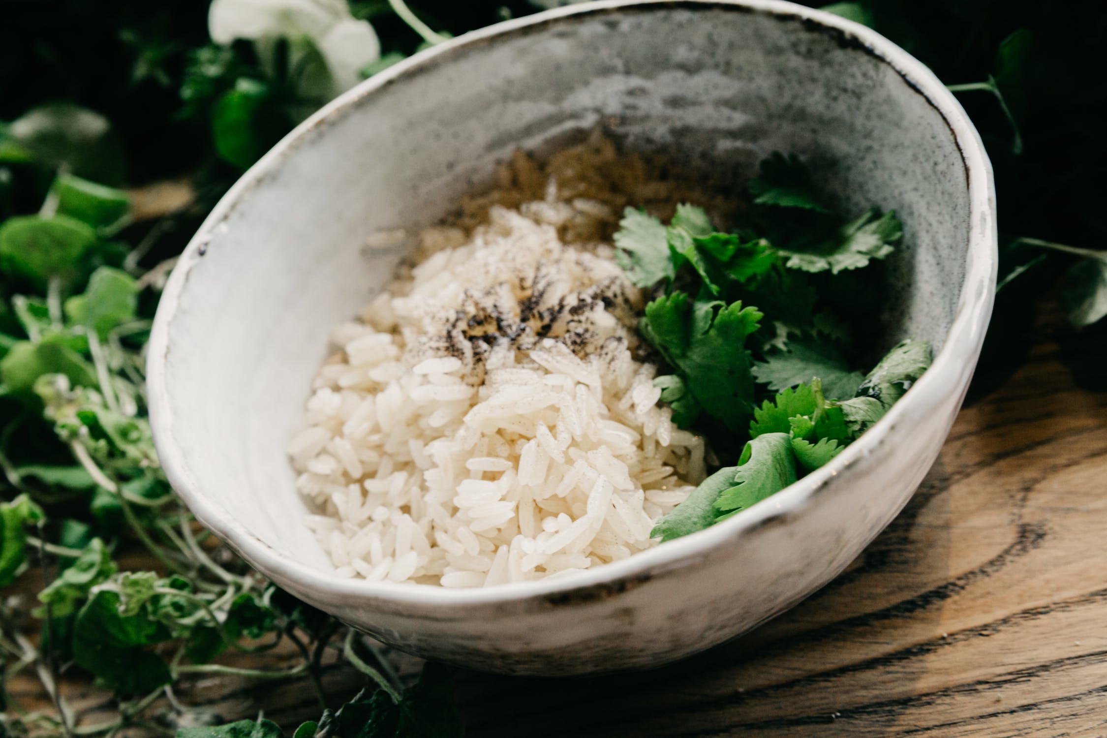 Cooked rice in a bowl with ground pepper and fresh cilantro.