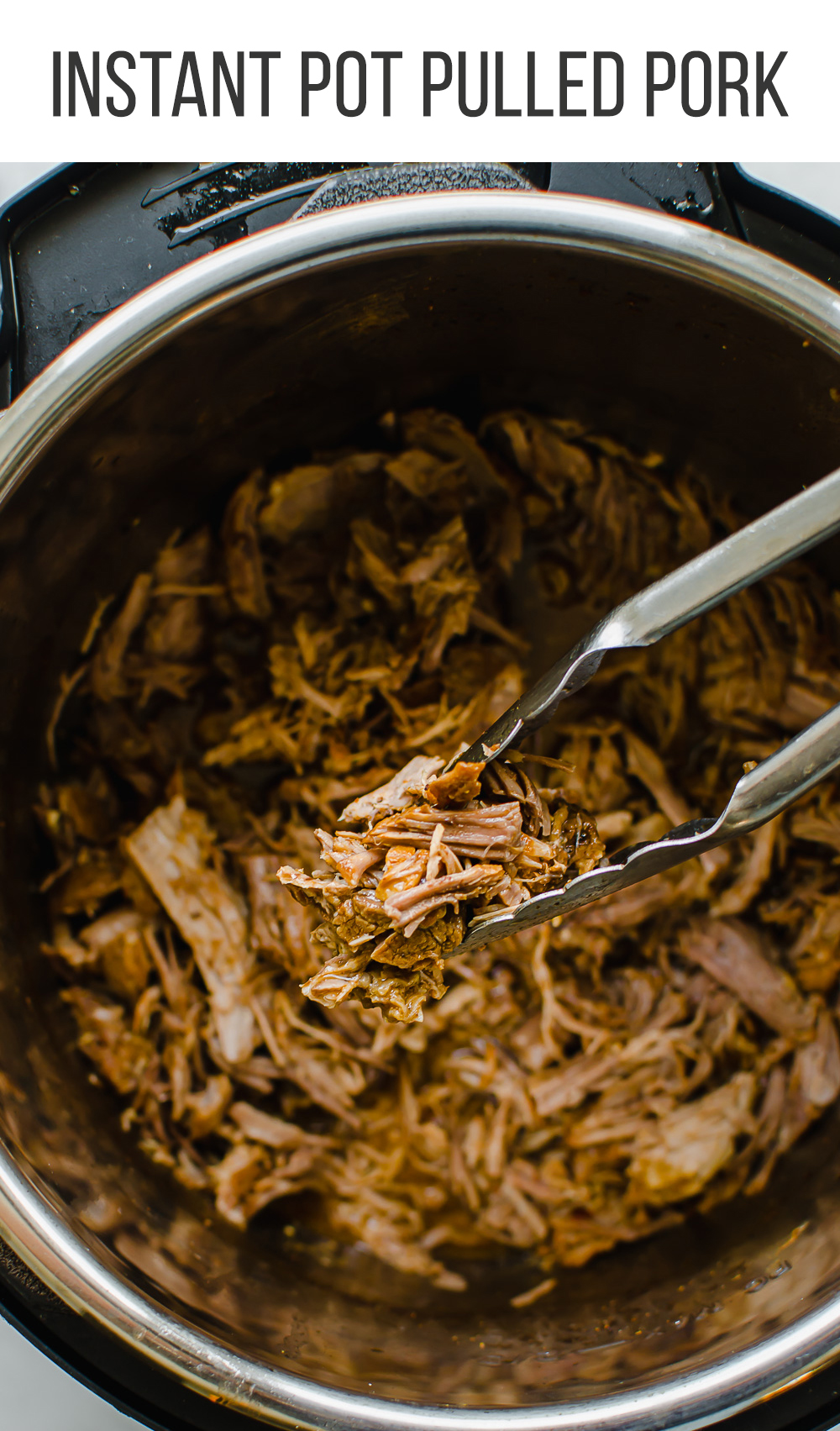 Pulled pork in the instant pot with tongs holding a serving.