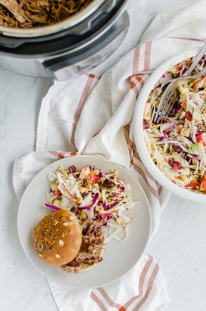 Freezer friendly Instant Pot Pulled Pork Sandwich on a white plate with an asian salad