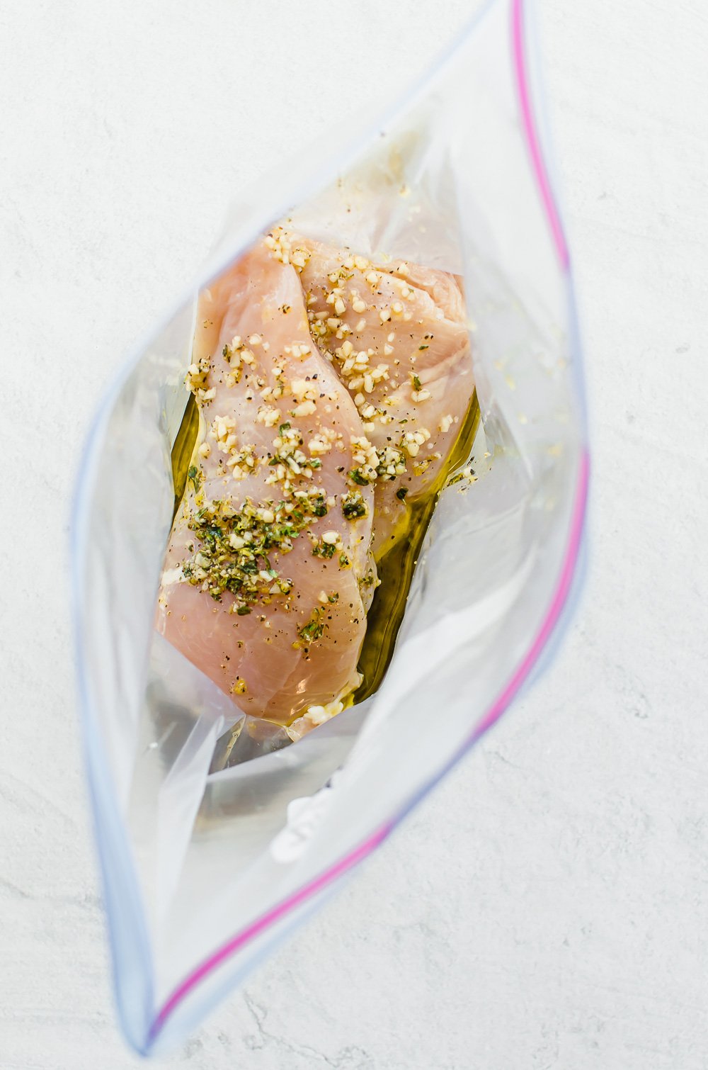 Looking into a freezer bag with chicken breasts in lemon garlic marinade.
