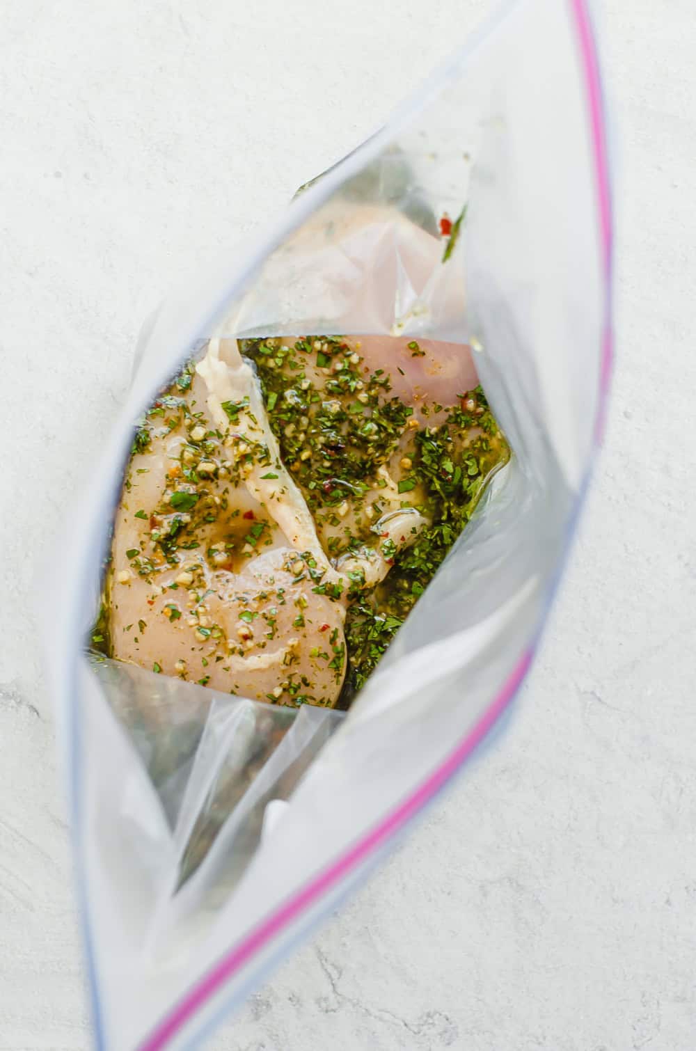 Raw chicken breasts in a freezer bag with cilantro lime marinade.