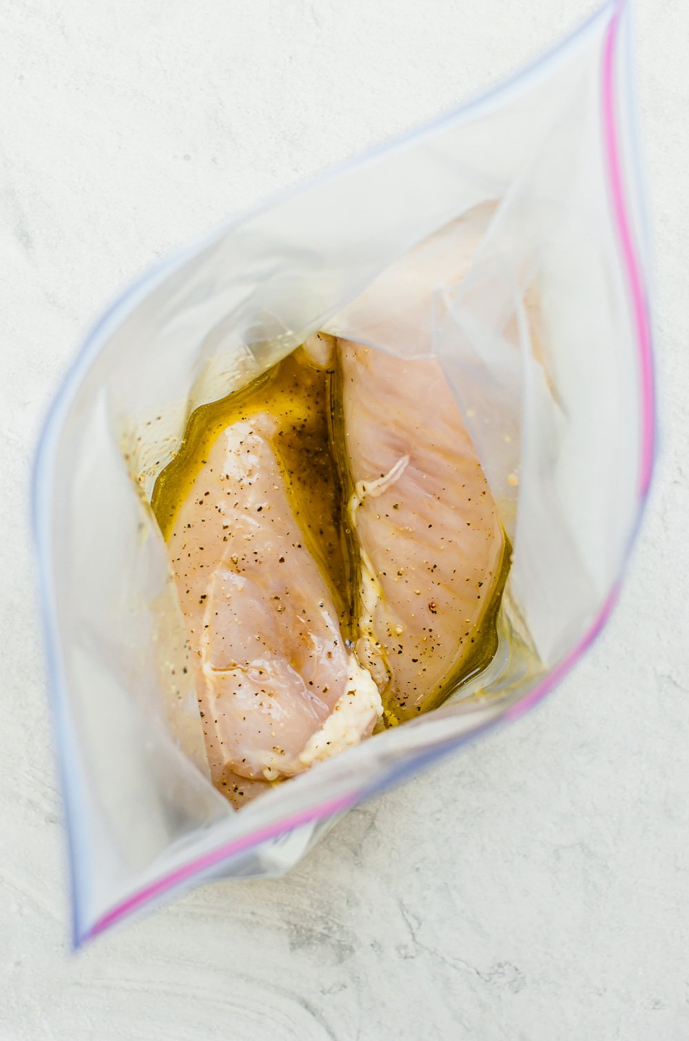 Savory chicken marinade in a freezer bag with chicken breasts.