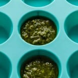 Pesto being frozen in a mini muffin tin.