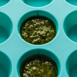Pesto being frozen in a mini muffin tin.