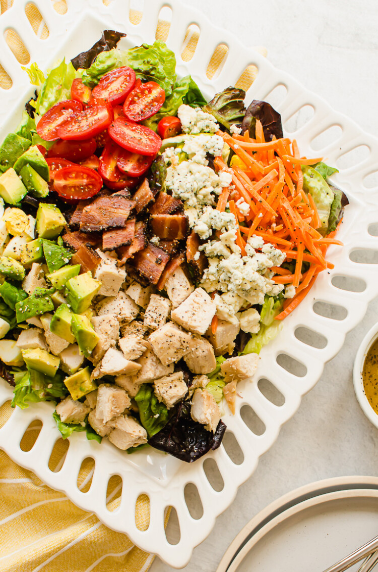 summer meal prep ideas - cobb salad on a white plate with yellow napkin and dressing on the side