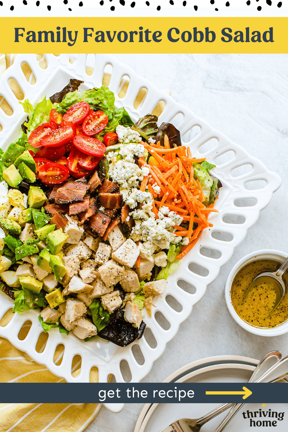 Cobb salad on a white plate with salad dressing on the side.