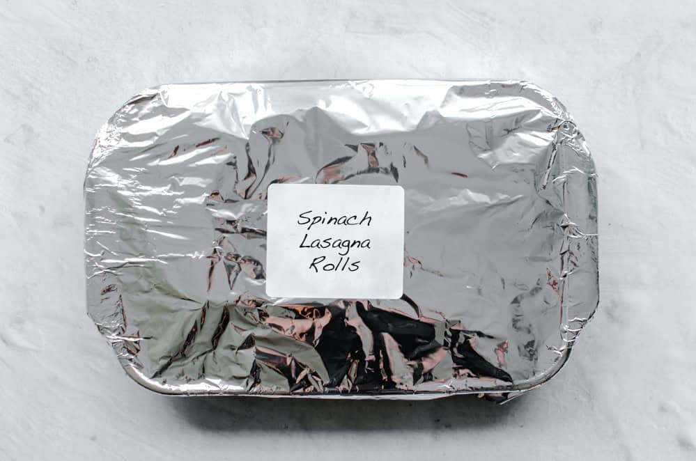 Spinach Lasagna Rolls in a freezer container covered with foil