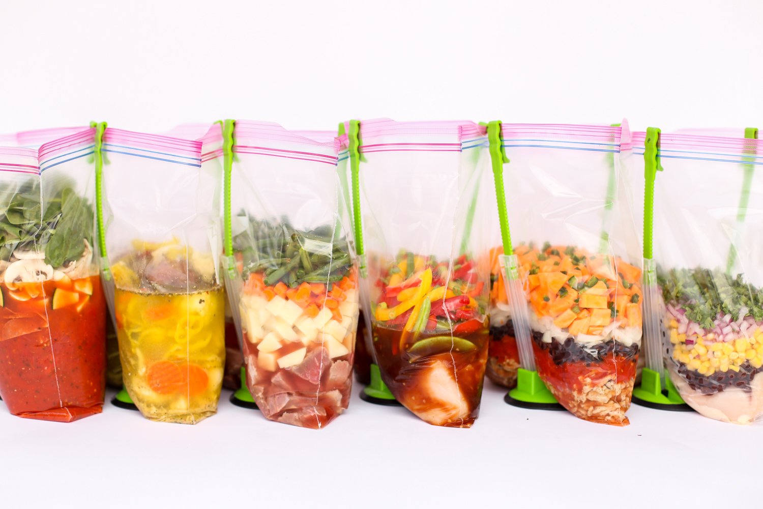 Open freezer meal bags with various ingredients being held open by bag holder stands.