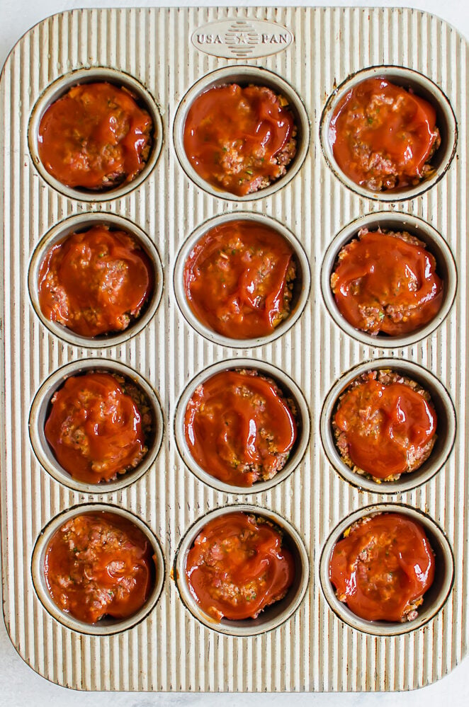 Meatloaf mixture in a muffin tin ready to bake.