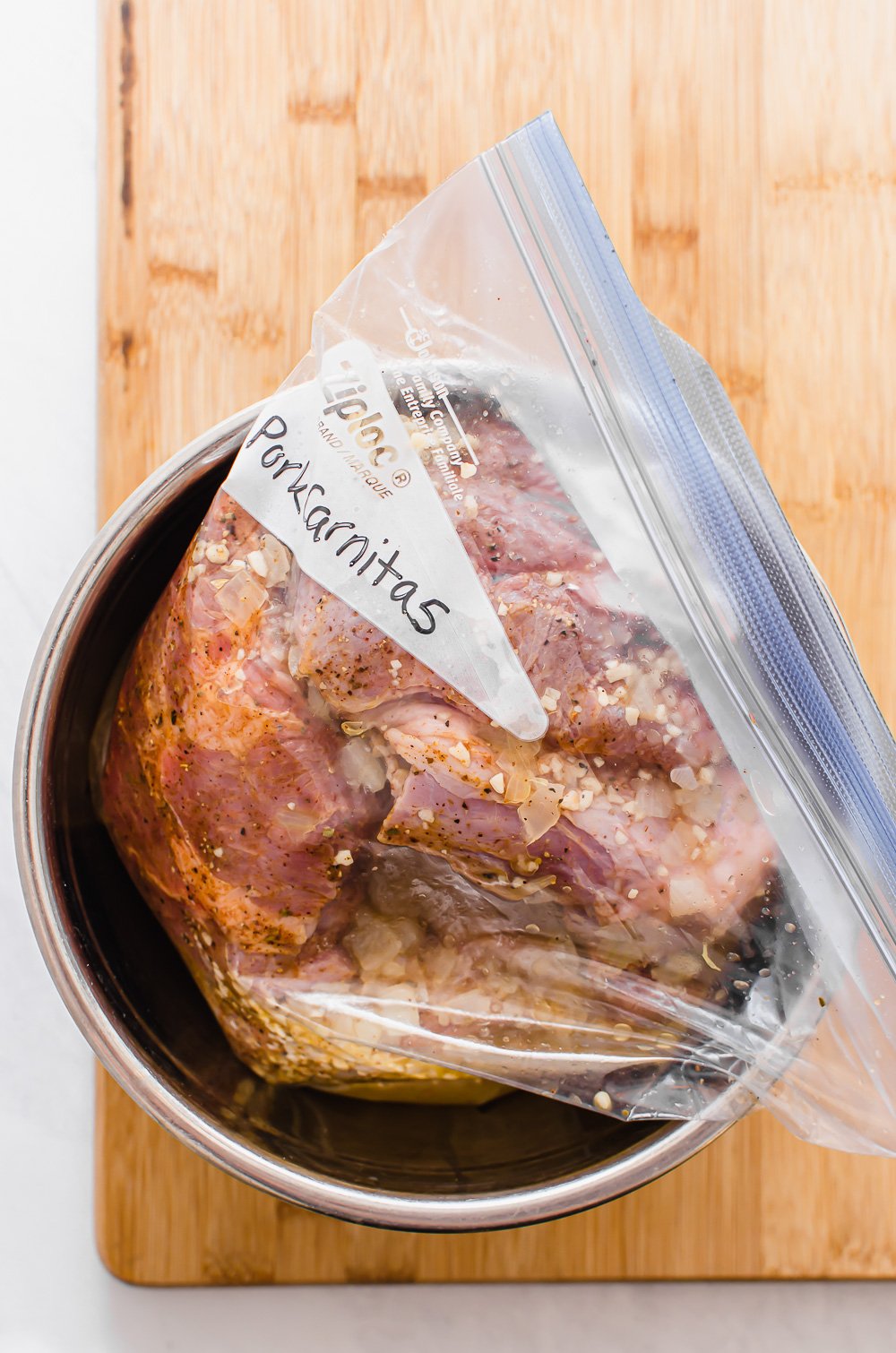 Pork shoulder with seasonings in a freezer bag labeled Pork Carnitas.