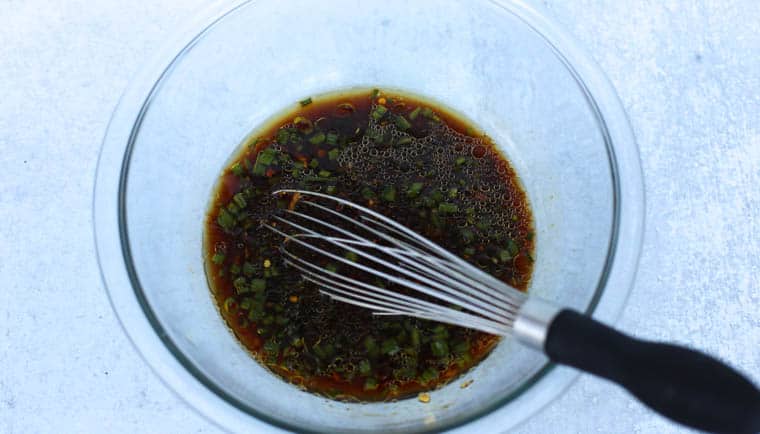 Ingredients for honey bourbon chicken being whisked in a glass bowl.