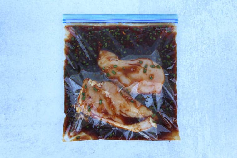 Chicken breasts in a honey bourbon marinade inside a freezer bag.