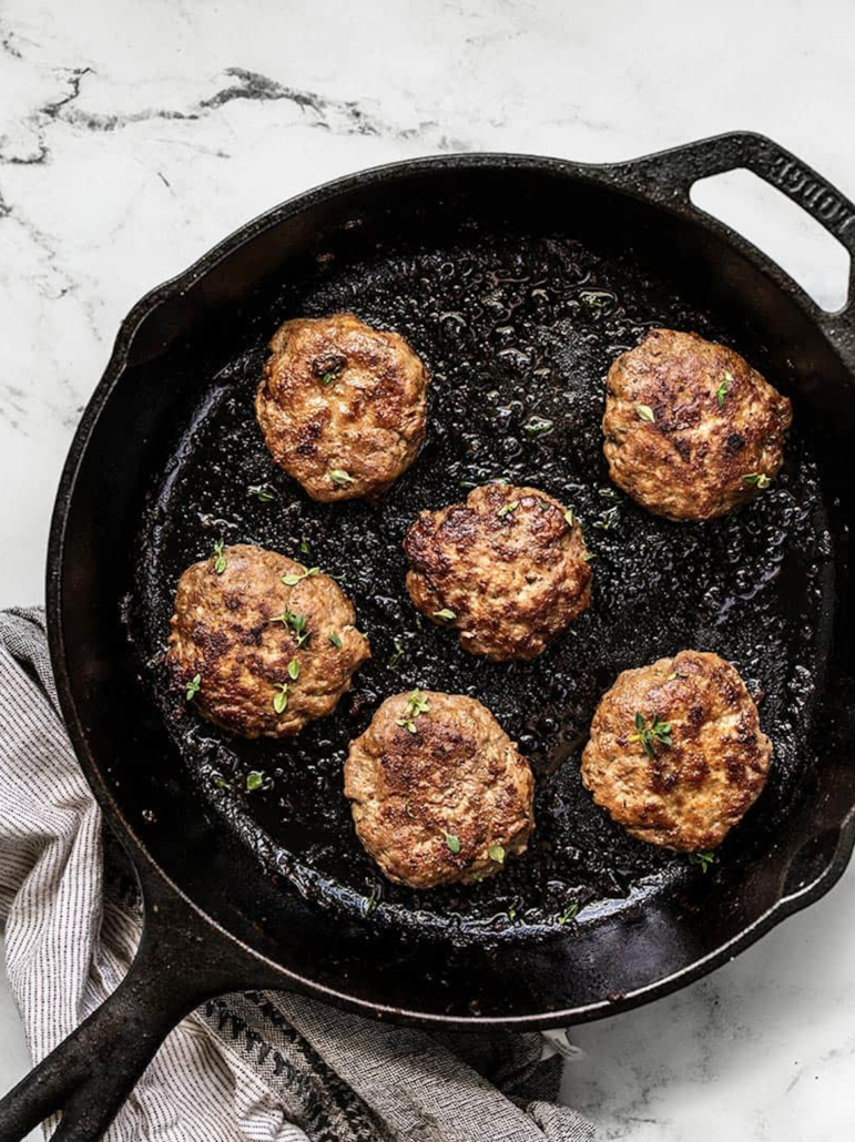 sausage patties cooking in a cast iron skillet