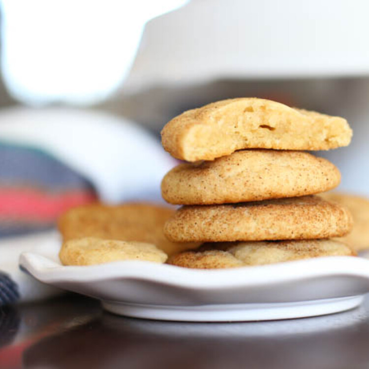 A stack of snickerdoodle cookies with the top on missing a bite.