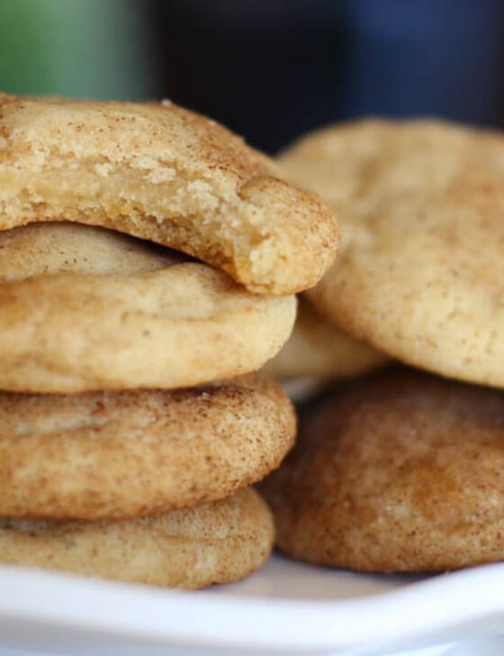 Snickerdoodle cookies stacked with the top one missing a bite.