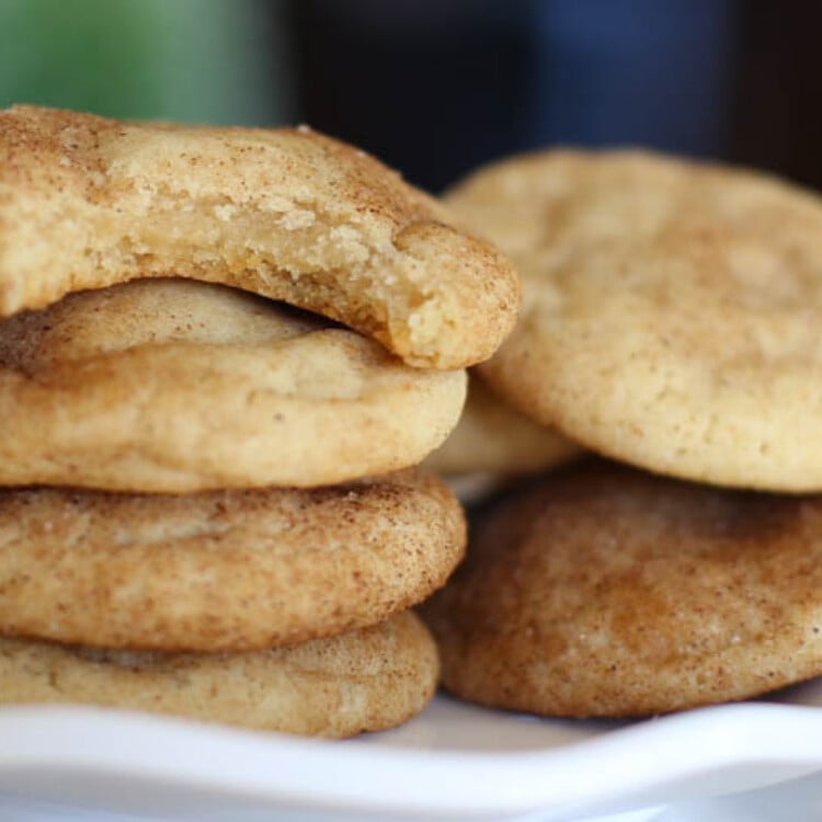 Snickerdoodle cookies stacked with the top one missing a bite.