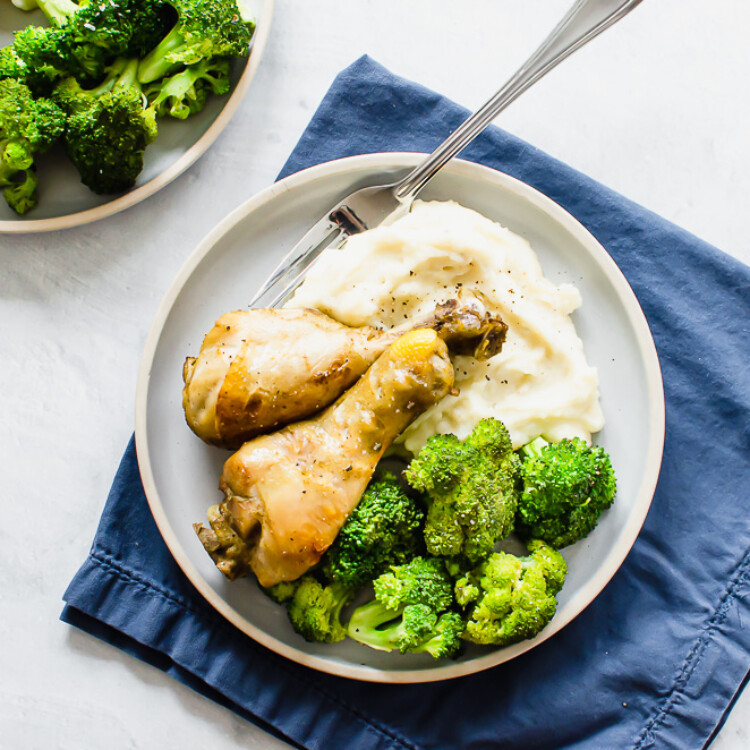 Baked chicken drumsticks on a plate with broccoli and mashed potatoes.