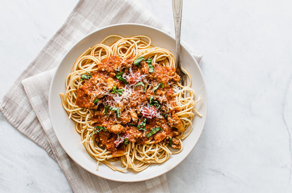 Whole wheat spaghetti with meat sauce and basil on top