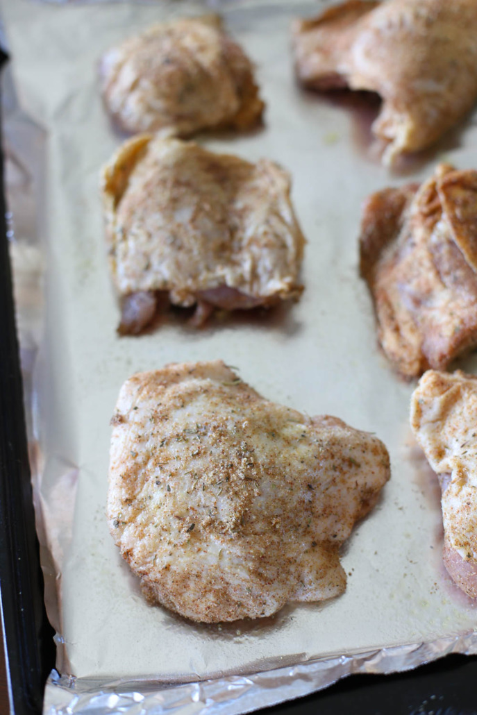 Raw chicken thighs on a foil lined baking sheet