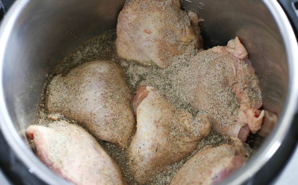 Chicken thighs in an Instant Pot with seasoning.