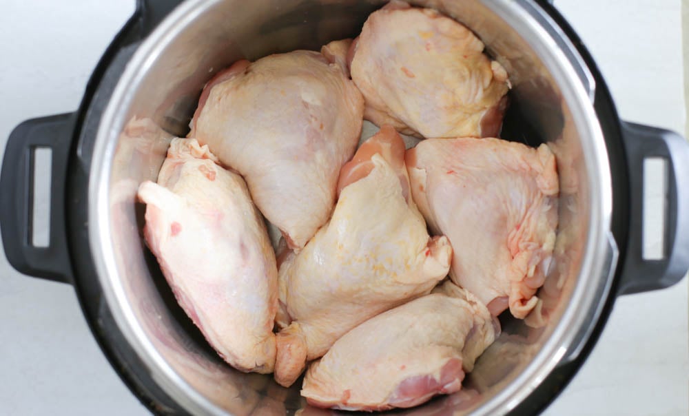 Frozen chicken thighs in an instant pot, touching each other, but not stacked.