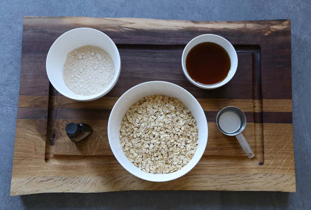 Ingredients for homemade granola measure in bowls and setting on a wooden cutting board.