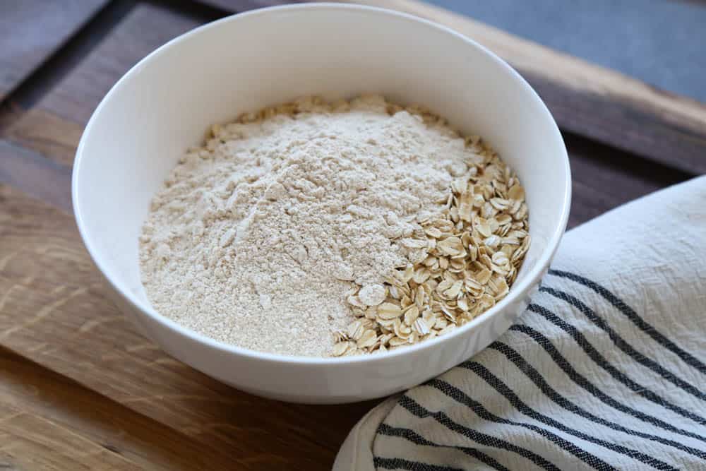 Oats and flour in a white bowl ready to mix with more ingredients.