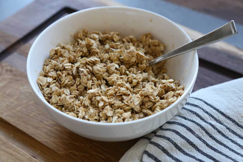 Wet and dry ingredients mixed together in a white bowl ready to be baked into homemade granola.