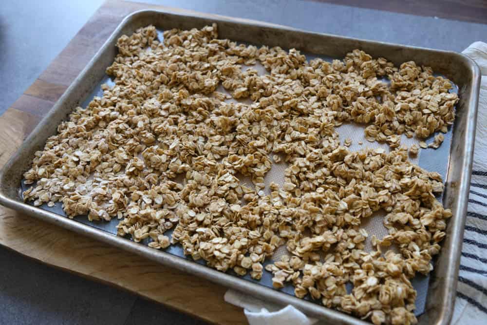 Homemade granola spread out on a sheet pan ready to go in the oven.