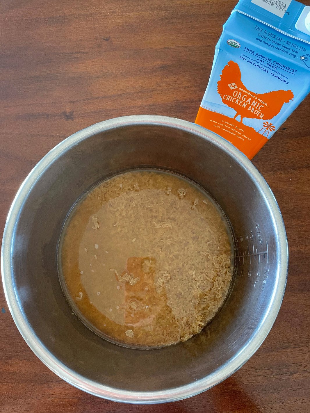 Brown rice and chicken stock in an instant pot steel bowl.