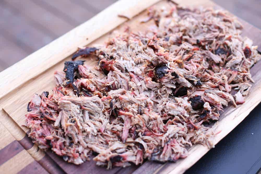 Shredded smoked pork on a wooden cutting board.