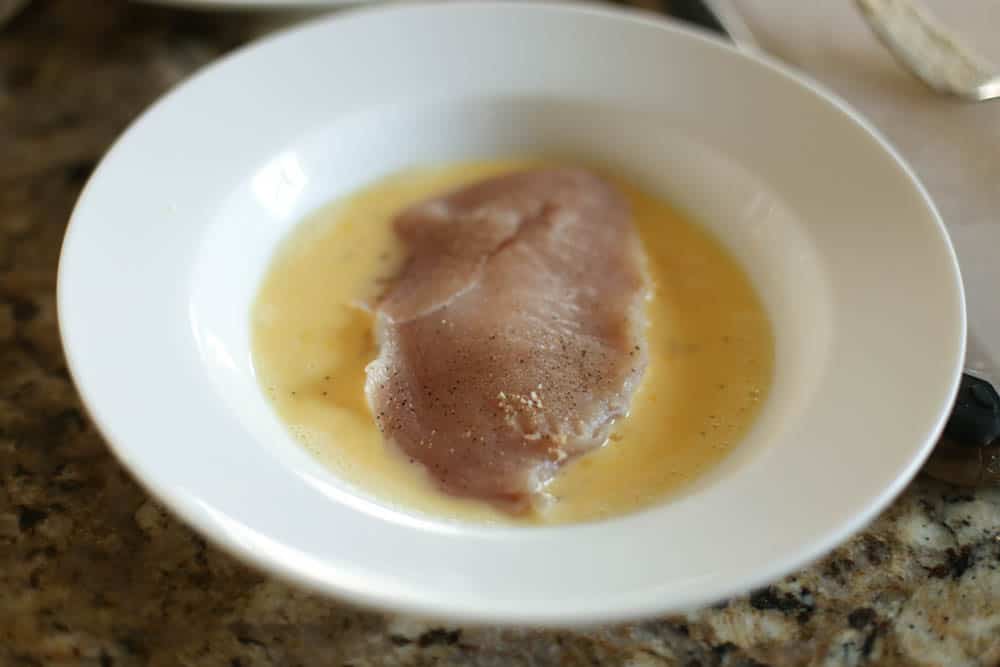 Chicken breast being tossed in egg