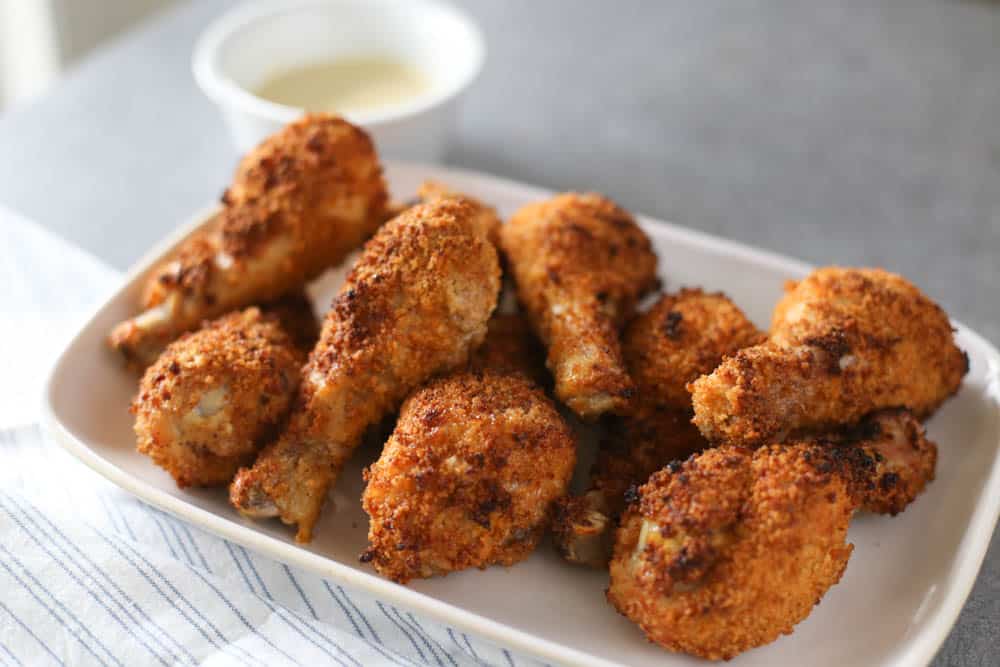 Crispy Baked Drumsticks on a white platter with a small bowl of honey mustard sauce.