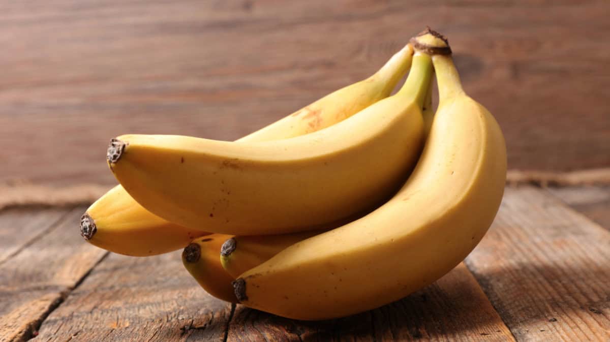 Bunch of bananas sitting on a wooden table.