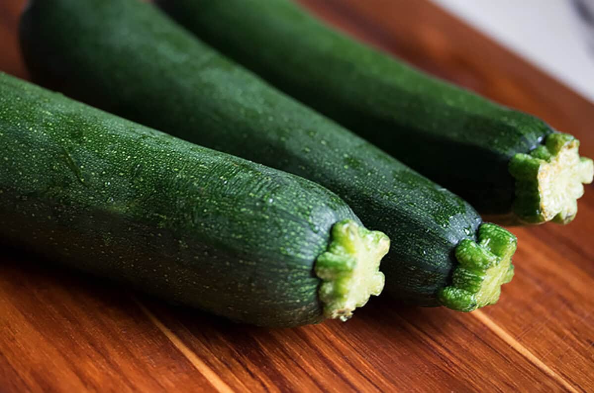 Three whole zucchinis on a table.