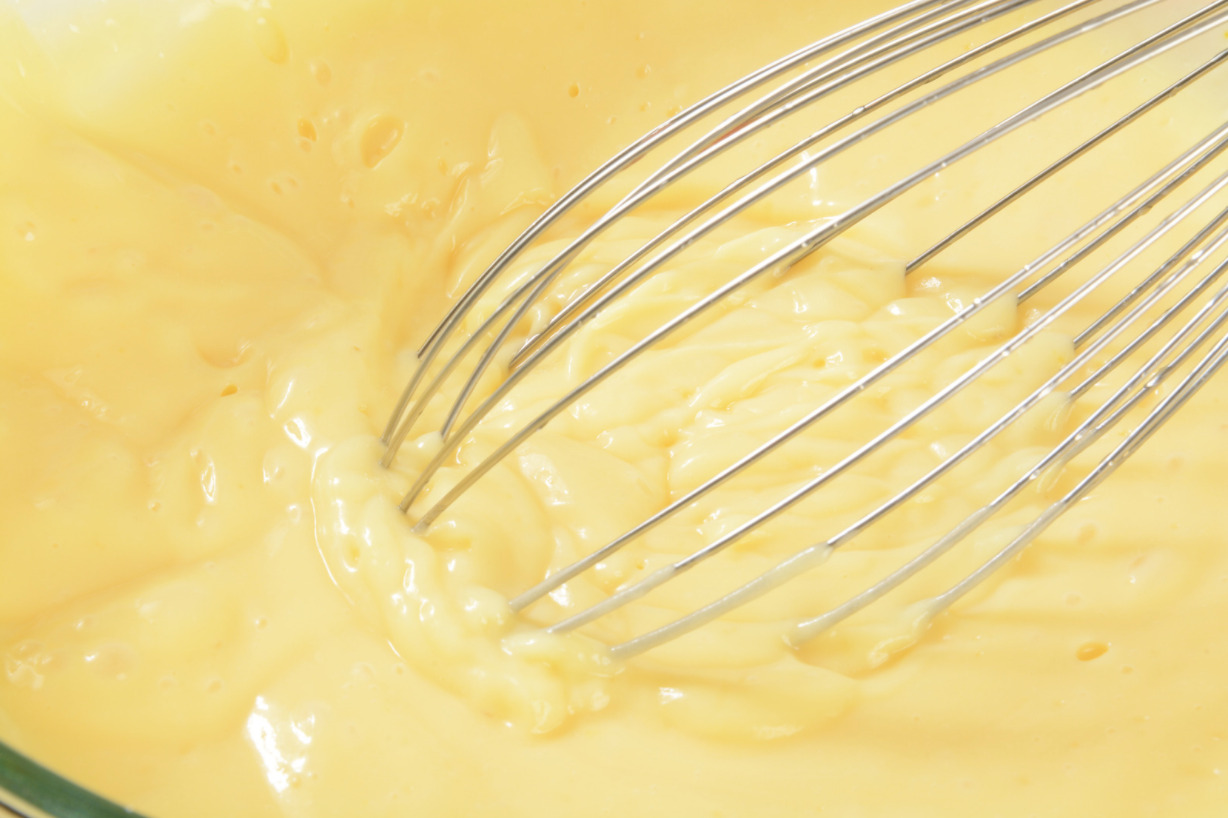 Vanilla pudding being mixed with a whisk.