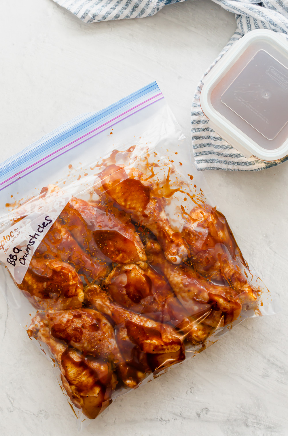 Chicken drumsticks covered in BBQ sauce in a gallon-size freezer bag.