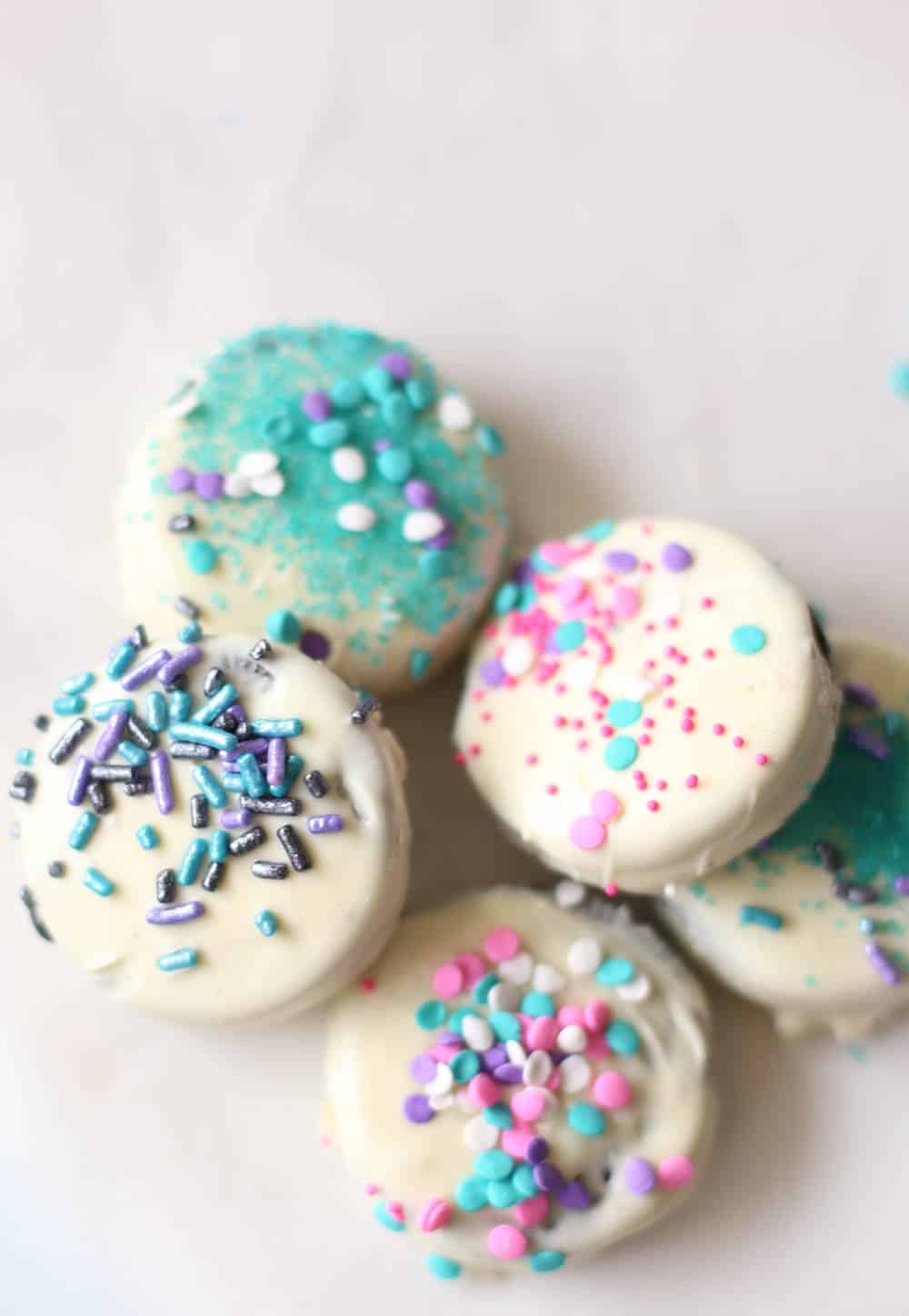 White chocolate covered Oreos with sprinkles in a pile.