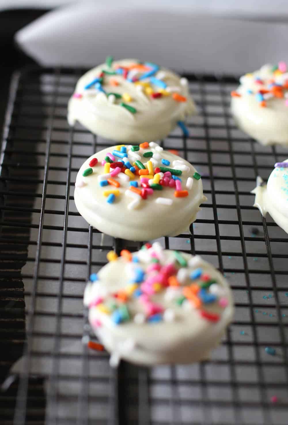 White chocolate covered Oreos with sprinkles on a baking sheet.