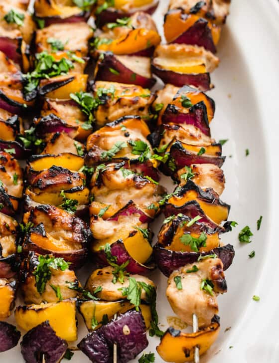 Cooked Honey garlic chicken kabobs on a white platter.